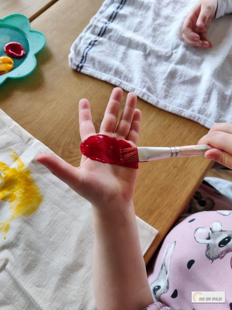 Die Handflächen werden mit Textilfarbe bemalt